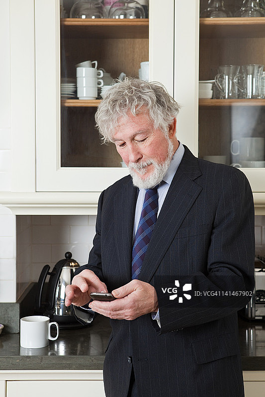 高级商人在厨房用智能手机图片素材