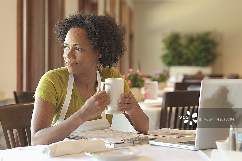 一位非裔美国妇女坐在餐桌前处理文书工作图片素材