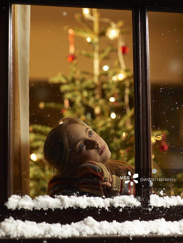 凝望窗外圣诞节的女孩。图片素材