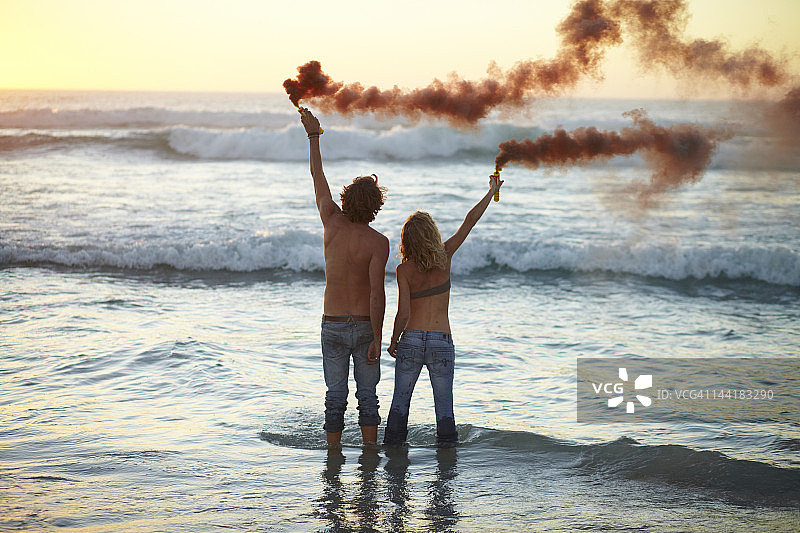 一对夫妇站在海里拿着烟雾弹图片素材