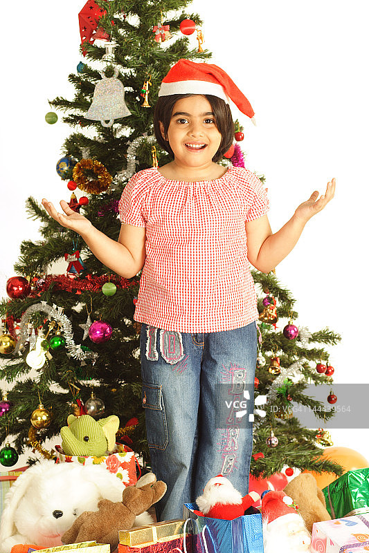 一个在圣诞树下拿着礼物的女孩的肖像图片素材