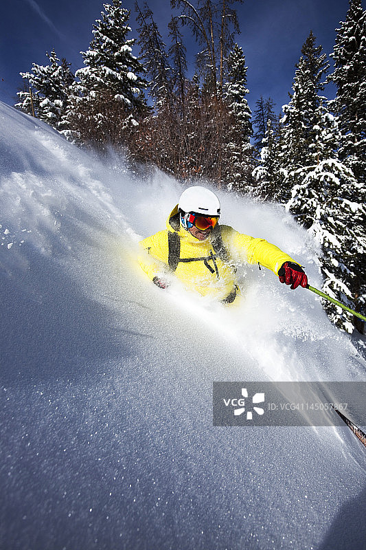 在科罗拉多州一个阳光明媚的日子里，一名运动滑雪者撕开了新鲜的粉末。图片素材