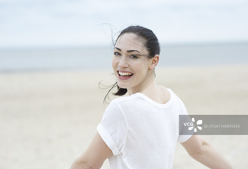 在海滩上伸开双臂的女人。图片素材