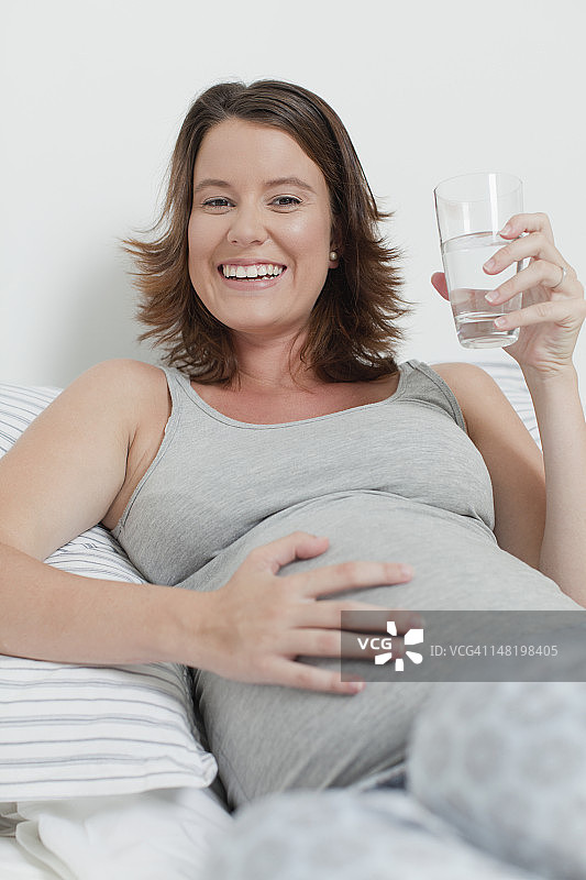 女人抱着怀孕的肚子躺在床上图片素材