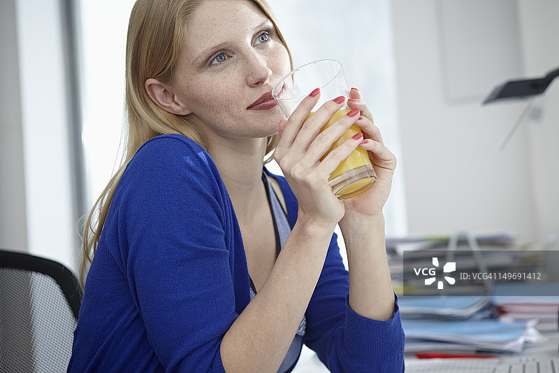 德国，科隆，公寓里喝果汁的年轻女子图片素材