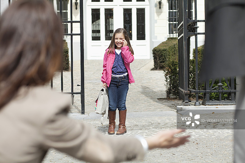 一位妇女在学校门口热烈欢迎她的女儿图片素材