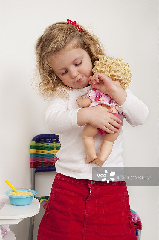 三岁金发女孩抱着她的娃娃图片素材