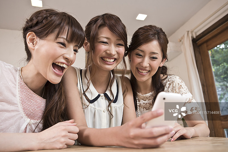三个年轻女人一起看智能手机图片素材
