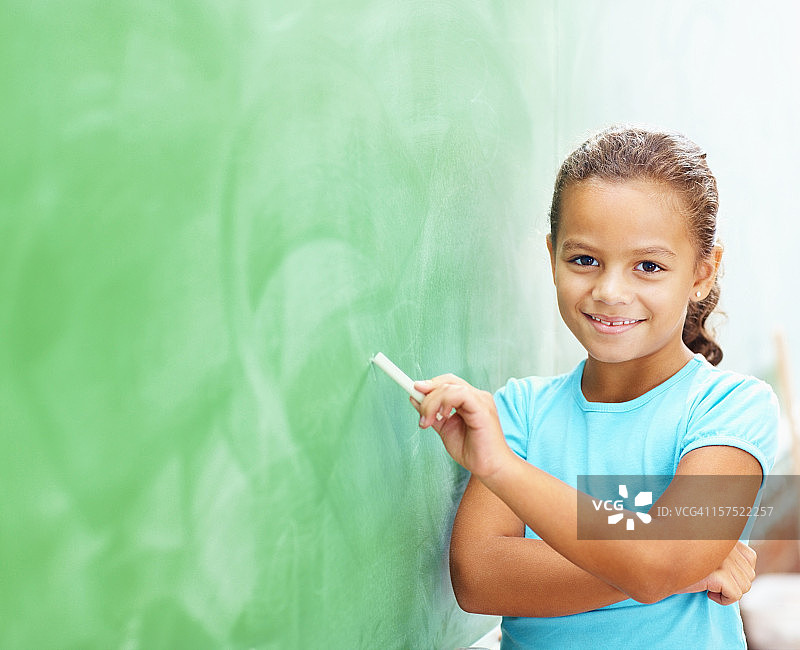 女学生用粉笔在黑板上写字图片素材