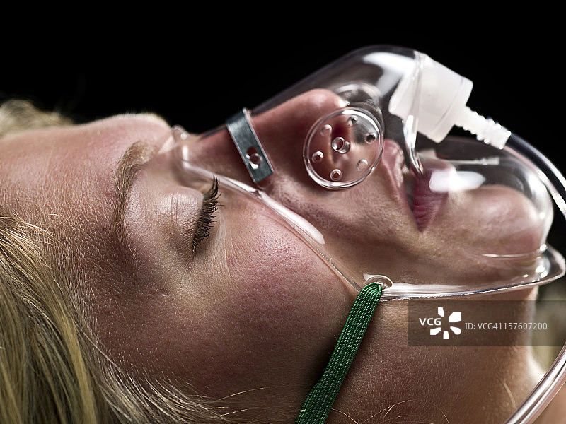 一个戴着氧气面罩的女性病人的特写。图片素材