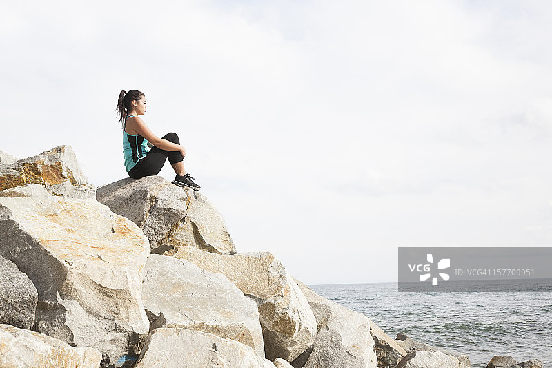 坐在岩石上俯瞰大海的女人图片素材