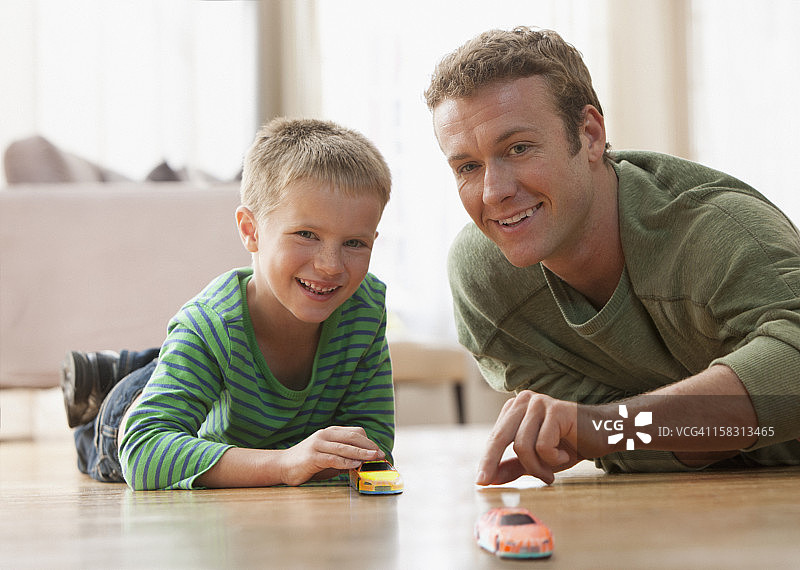 白人父亲和儿子在地板上玩玩具车图片素材