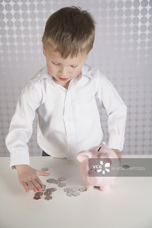 小男孩在存钱罐里存钱。图片素材