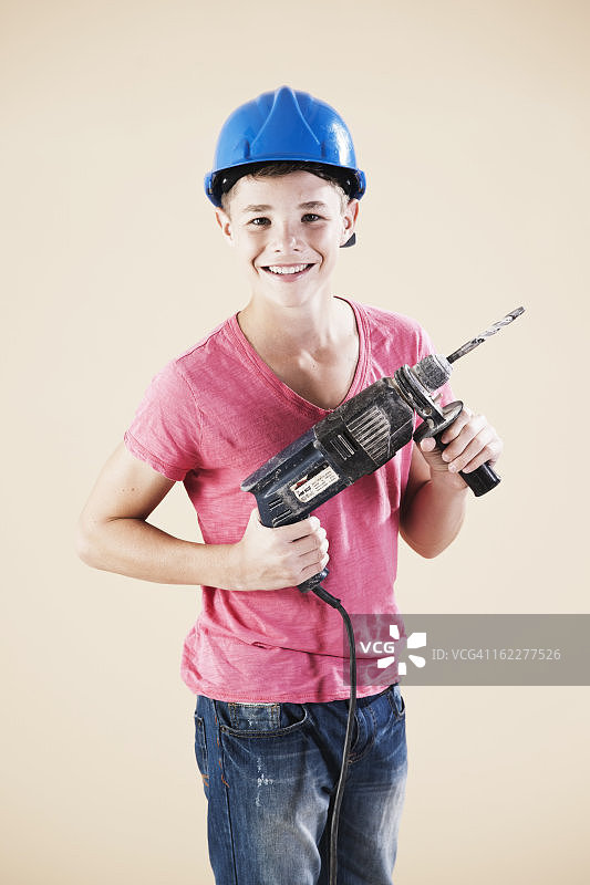 十几岁的男孩，戴着头盔和钻机图片素材