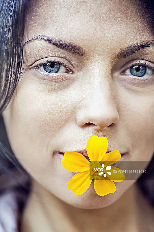 一个年轻女子嘴里叼着一朵黄花图片素材