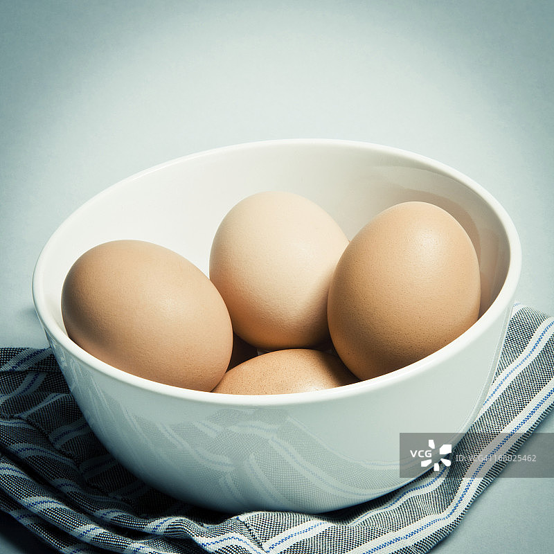 一组新鲜的鸡蛋在白碗里站在破布上图片素材