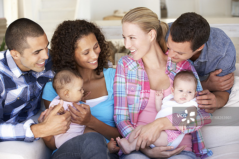 两个年轻的家庭和婴儿坐在家里图片素材
