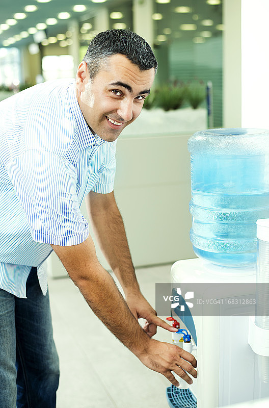 从饮水机里喝水的商人图片素材
