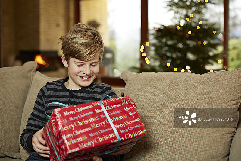 快乐的男孩看着圣诞礼物图片素材