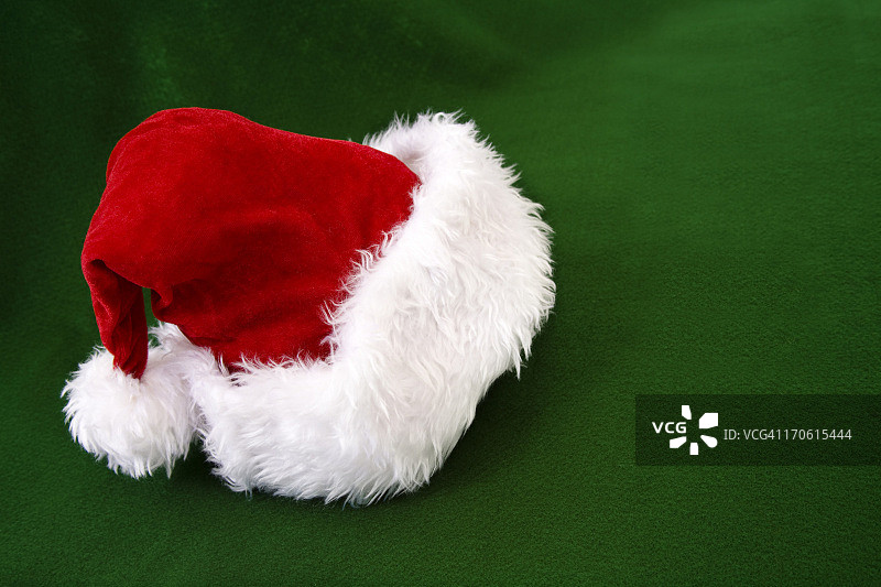 圣诞老人的帽子戴在绿色的毛毡上。圣诞节。Copyspace。图片素材