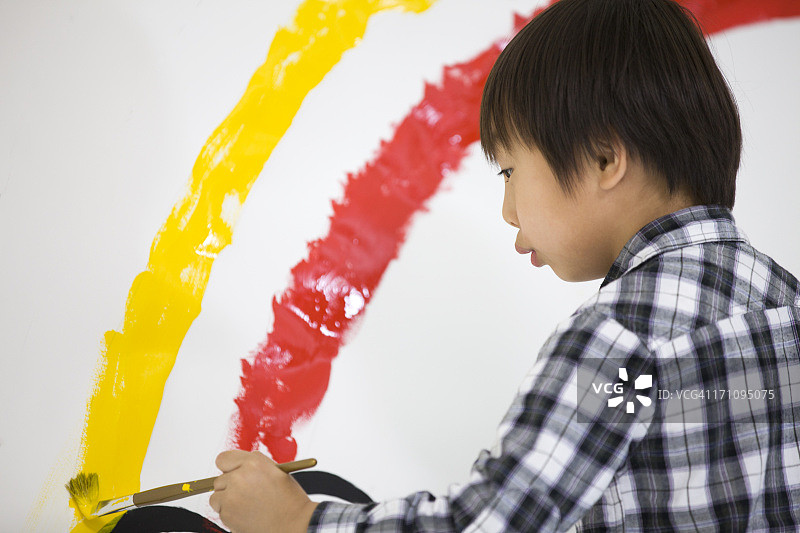 男孩在墙上画彩虹图片素材