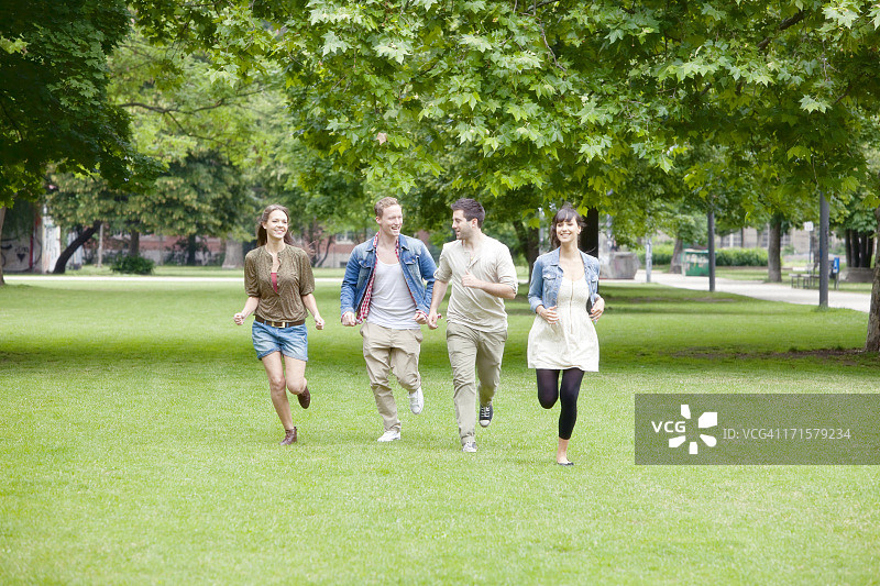 四个微笑的年轻人在公园里跑步图片素材
