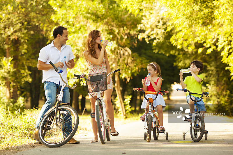 年轻的家庭在公园里骑自行车图片素材