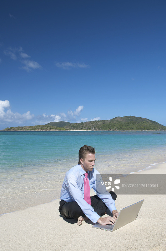 商人坐在空荡荡的沙滩上打字图片素材