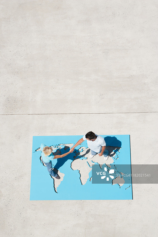 男人和女人在户外与世界地图握手的鸟瞰图图片素材