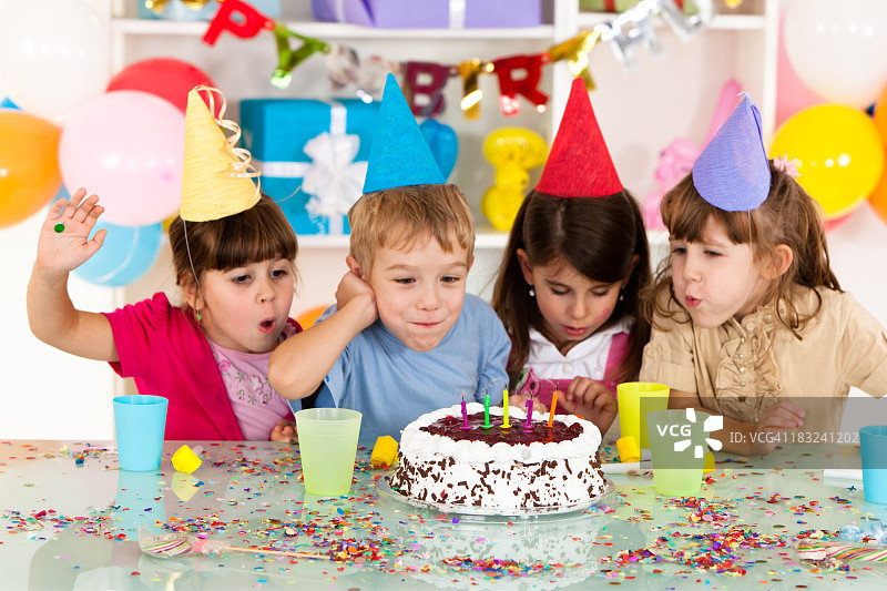 一群快乐的孩子在生日蛋糕上吹蜡烛图片素材