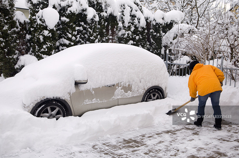 女人在铲被雪覆盖的汽车图片素材