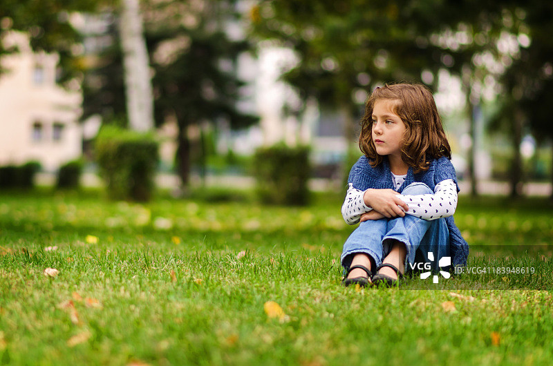 美丽的女孩坐在公园的草地上图片素材