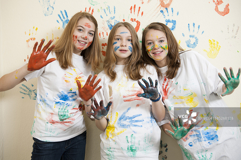三个女孩的手和墙上都涂了颜料图片素材