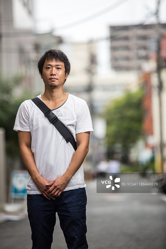一个三十多岁的日本男人站在一个城市里图片素材