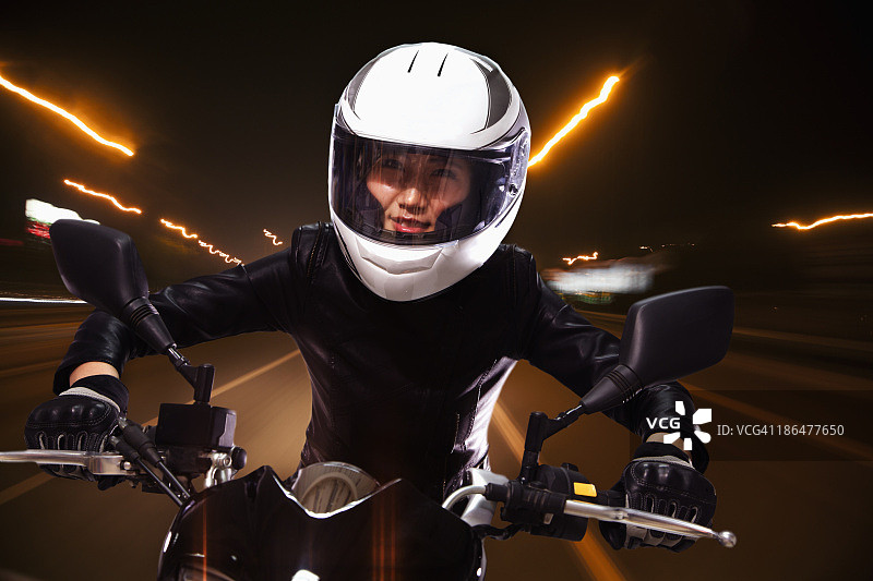 年轻女子骑着摩托车穿行在北京的街道上，小路轻盈图片素材