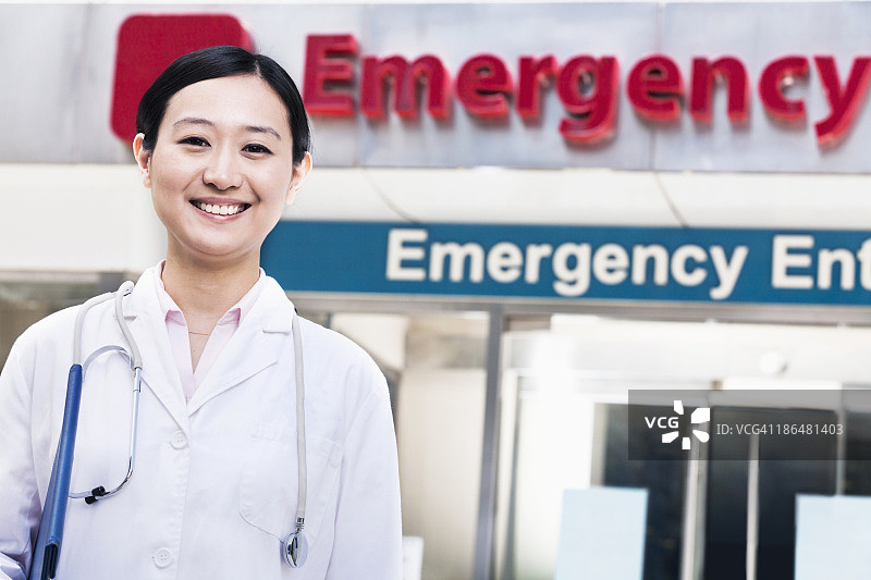 医院外微笑的女医生肖像，背景是急诊室的标志图片素材