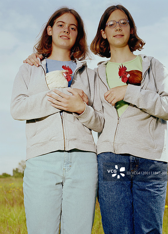 十几岁的姐妹(14-17岁)抱着宠物鸡在运动衫，肖像图片素材