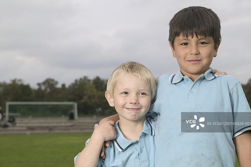 两个男孩(5-7岁)在操场上拥抱，微笑，肖像图片素材