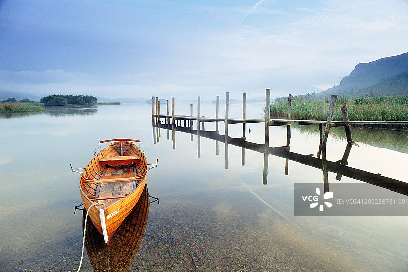 静寂的湖面上，木制码头旁的空划艇图片素材