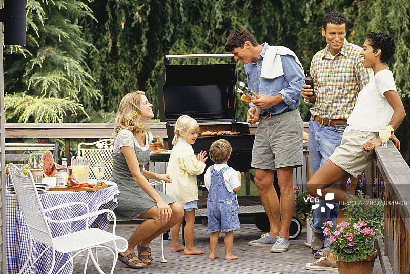 两对夫妇和两个孩子(2-3,4-5)在露台上烧烤图片素材