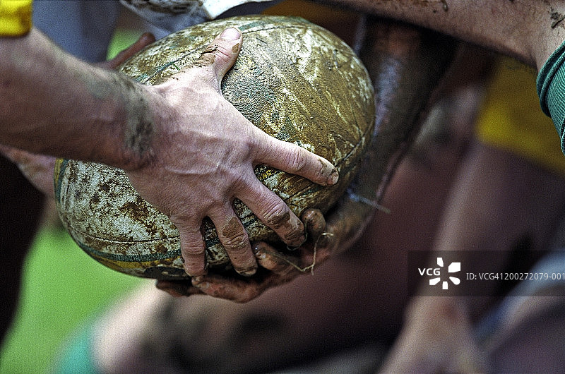 橄榄球运动员把泥球从腿上传过，特写图片素材