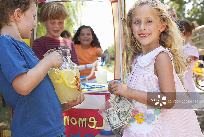 儿童(6-12岁)在柠檬水摊位，女孩(5-7岁)拿着钱，肖像图片素材
