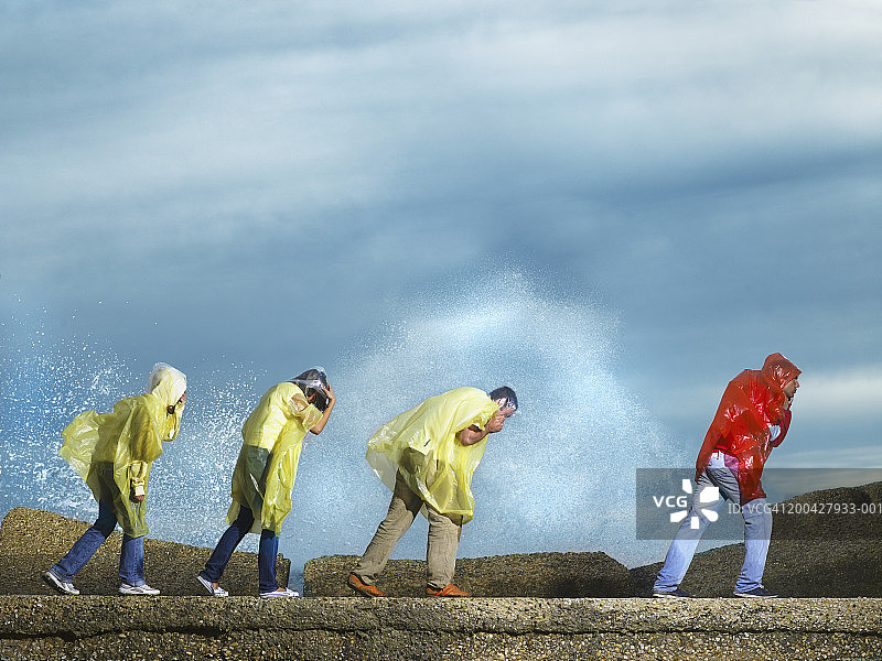 四个人穿着雨衣在海边户外，侧视图片素材
