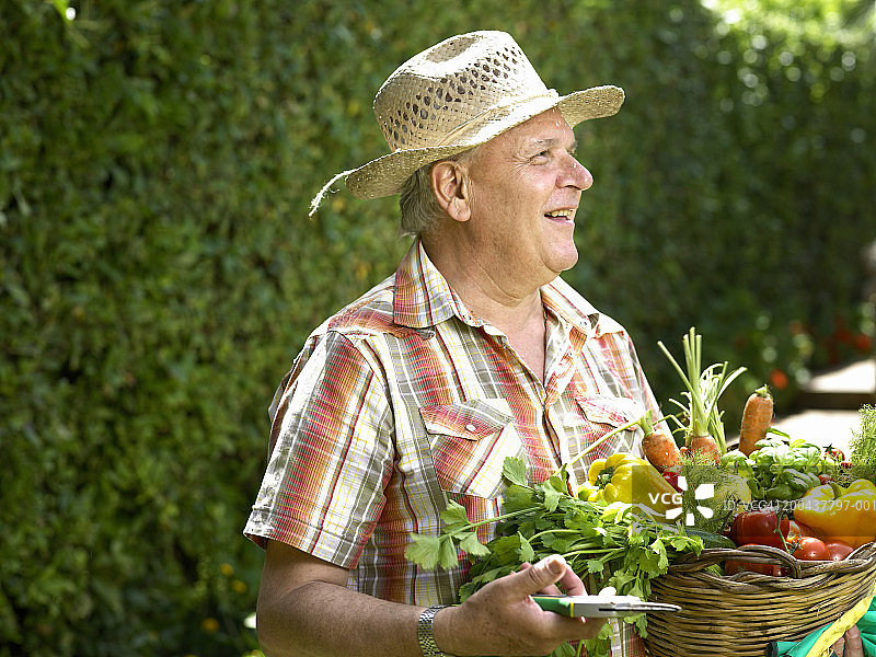 成熟的男人在花园里抱着一篮蔬菜图片素材