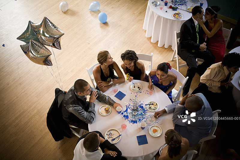 一群青少年(15-18岁)坐在毕业舞会的桌子旁，俯瞰高处图片素材