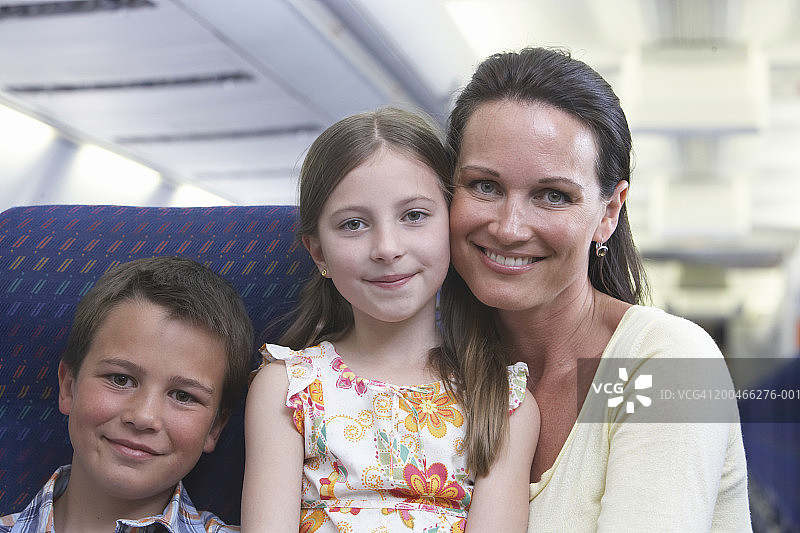 母亲和两个孩子(7-10)在飞机上，肖像图片素材