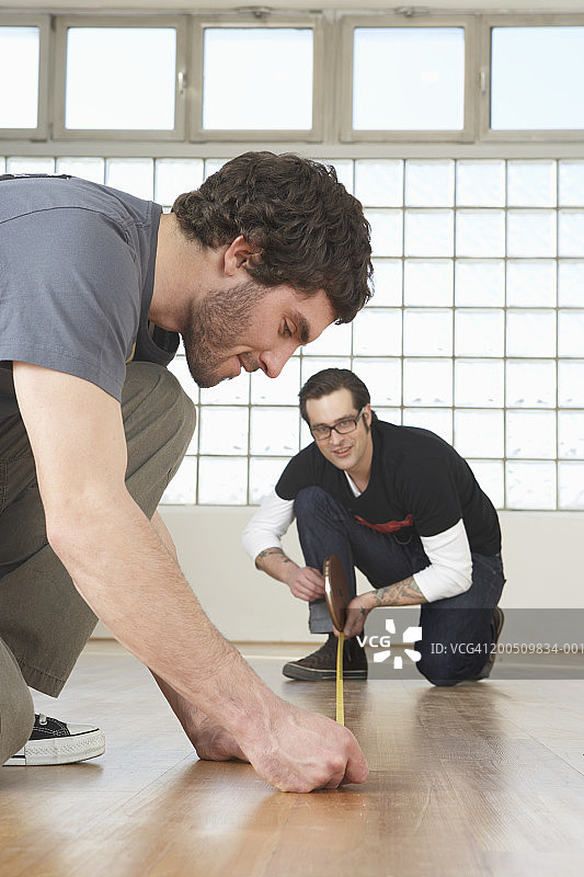 两个人沿着木地板测量图片素材