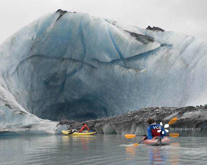 在美国阿拉斯加州瓦尔迪兹冰川的冰洞边皮划艇图片素材