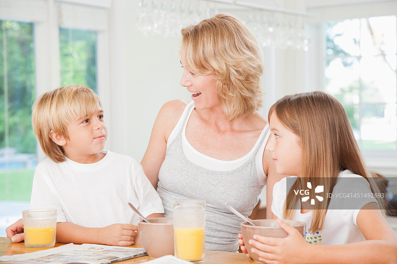 女人和两个孩子在厨房吃早餐图片素材