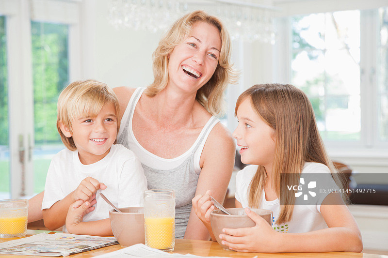 女人和两个孩子在厨房吃早餐图片素材